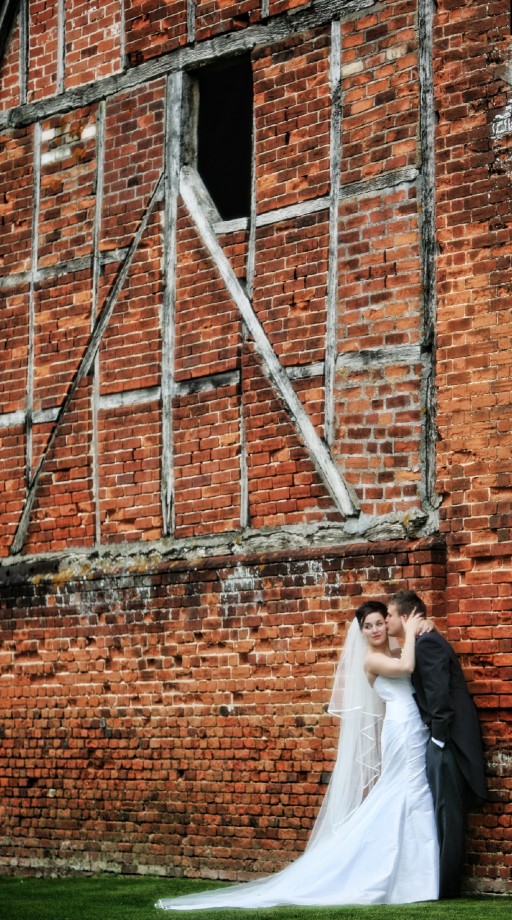 Bride and Groom kiss by Barn Wall