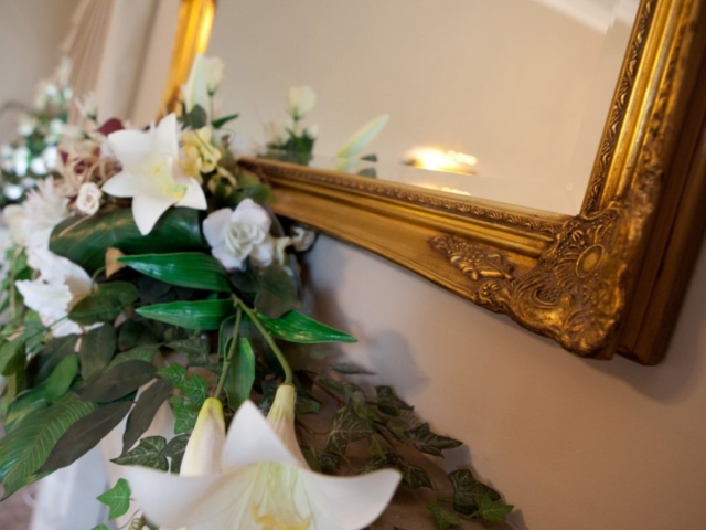 Gold painted mirror with flower bed on fireplace at wedding venue essex