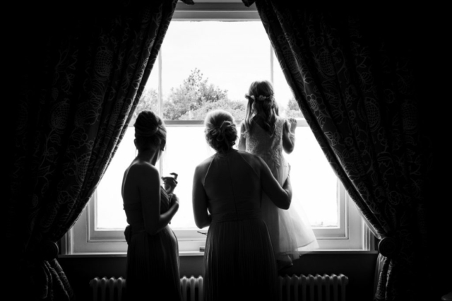 Bride, Bridesmaid and Child looking out of a window at wedding venue essex