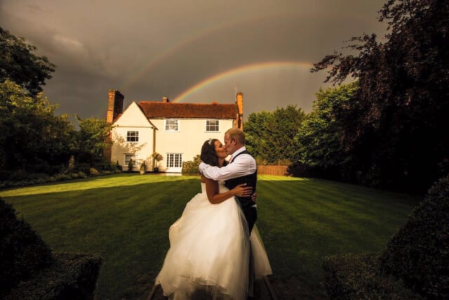 Bride and groom kiss under the rainbow